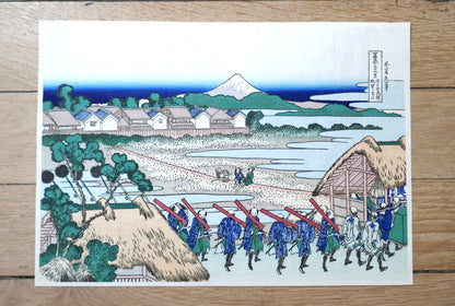 Estampe Hokusai 36 vues du Mont Fuji, Fuji vu du quartier des plaisirs de Senju, reproduction début Shōwa par Bijutsusha, cortège de samouraïs en uniforme bleu devant une maison de thé, format chūban