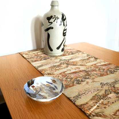 mise en scène d'une table avec une déco japonaise composée d'un maru obi en chemin de table d'une tokkuri et d'une assiette japonaise ancienne