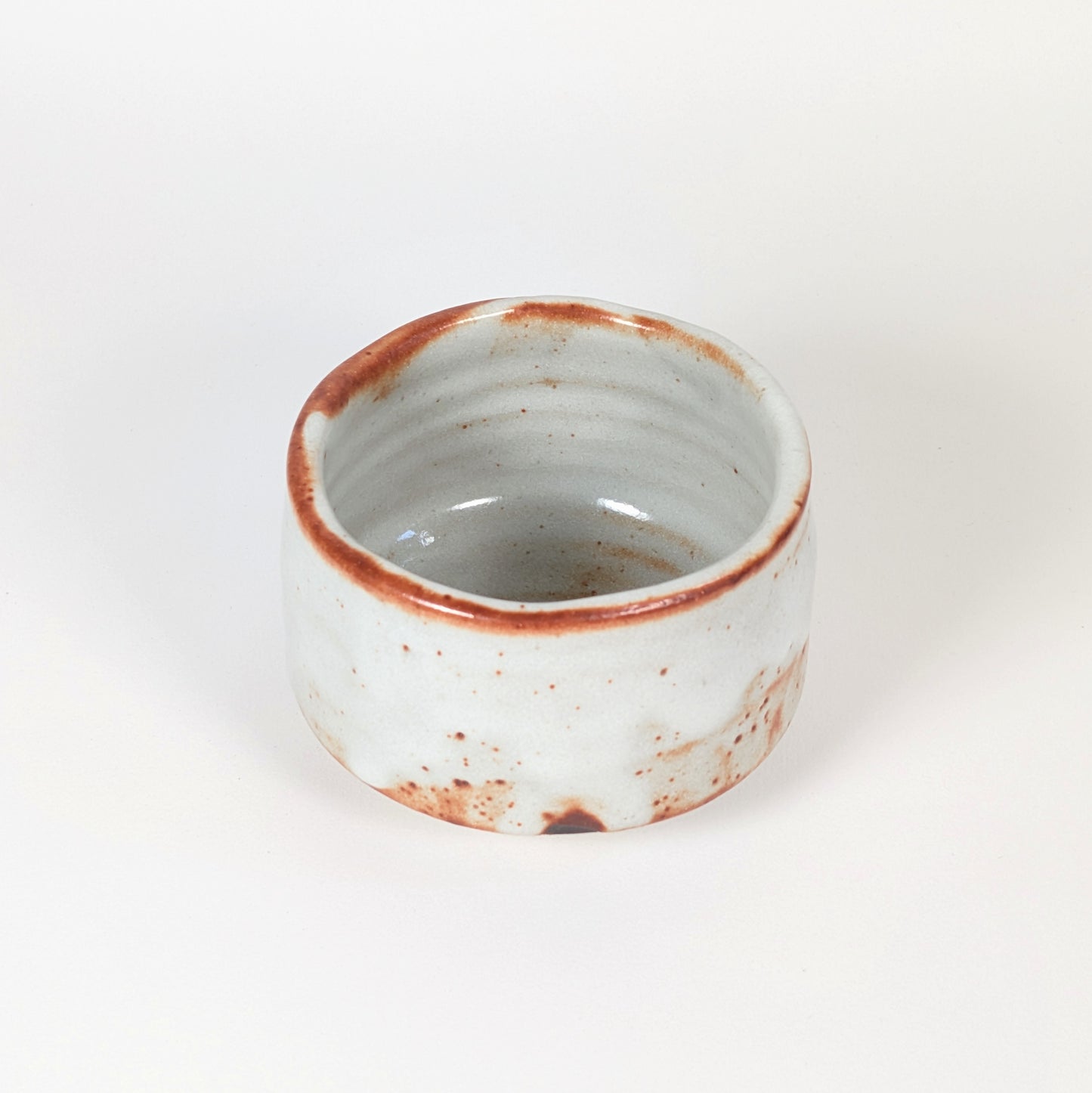 Vue intérieure du chawan Beni Shino, bol matcha artisanal japonais avec paroi tournée, glaçure claire et bord brun rouille.