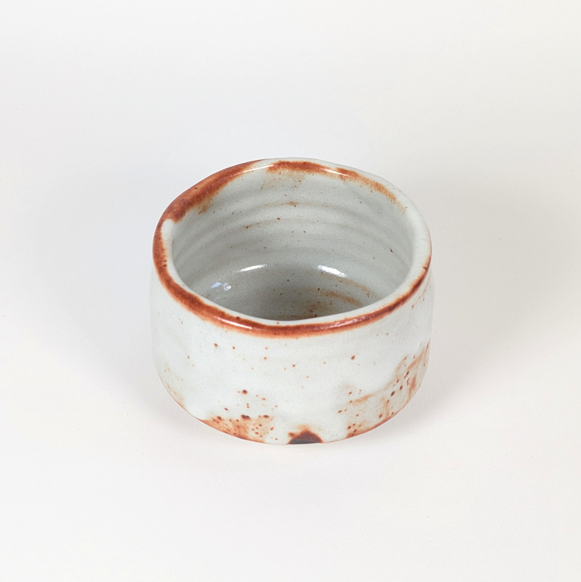 Vue intérieure du chawan Beni Shino, bol matcha artisanal japonais avec paroi tournée, glaçure claire et bord brun rouille.