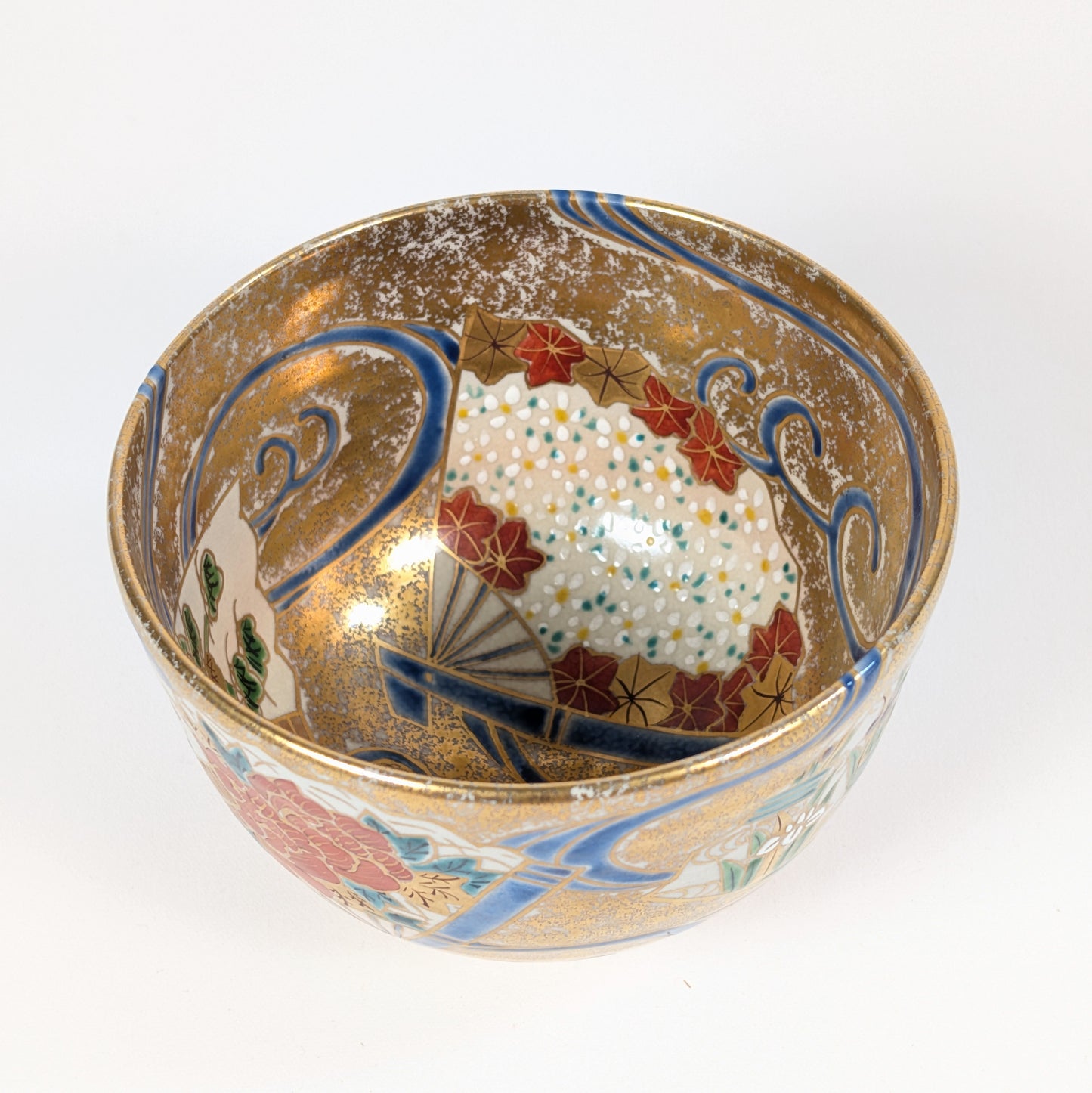 Vue intérieure du chawan, ou mikomi, avec éventail fleuri, feuilles d’érable momiji, vagues bleues et décor kinrande doré.