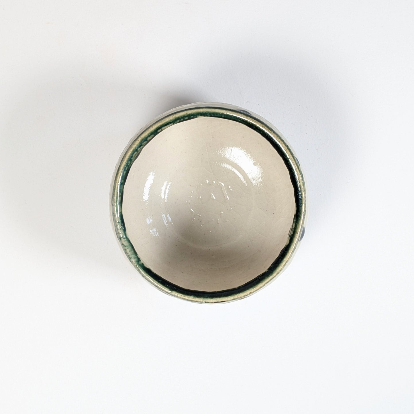 Intérieur d’un chawan Oribe, bol à thé japonais avec émail crème craquelé et bord vert au cuivre
