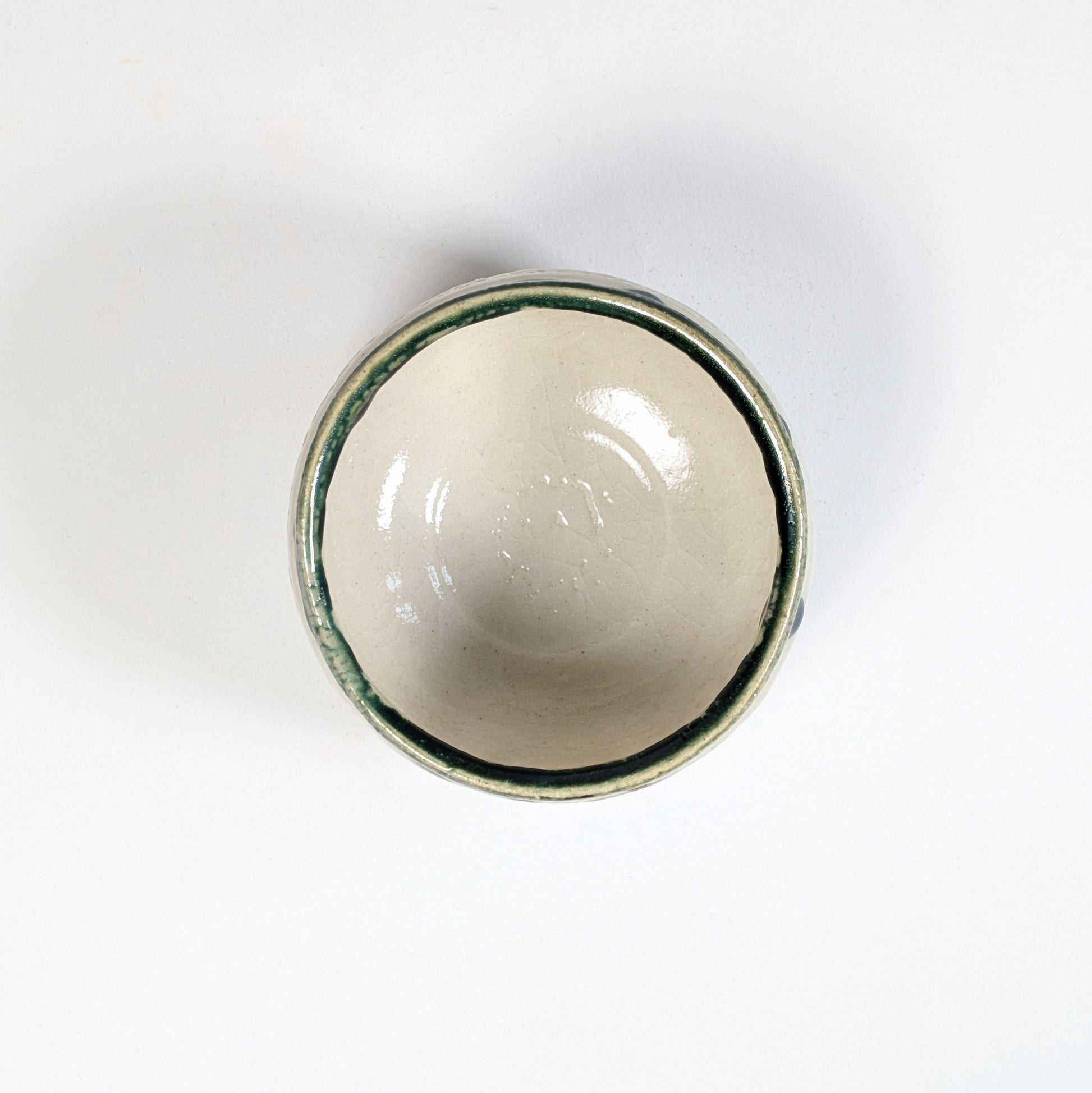 Intérieur d’un chawan Oribe, bol à thé japonais avec émail crème craquelé et bord vert au cuivre