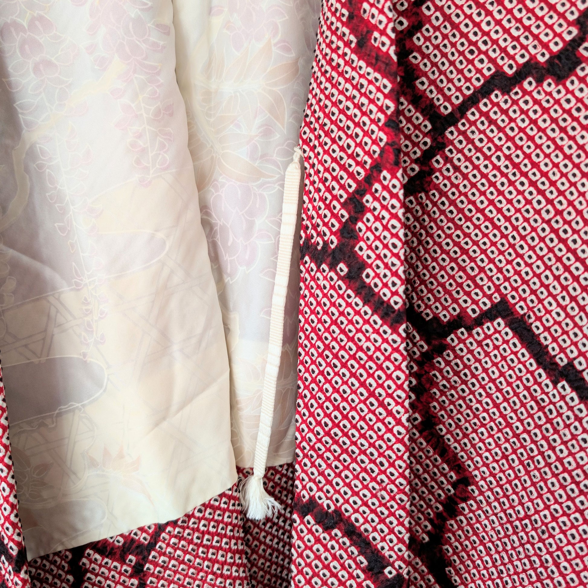 Détail intérieur d’un haori japonais 100% soie en shibori rose fuchsia avec himo blanc et doublure à motifs fuji, glycines japonaises pastel