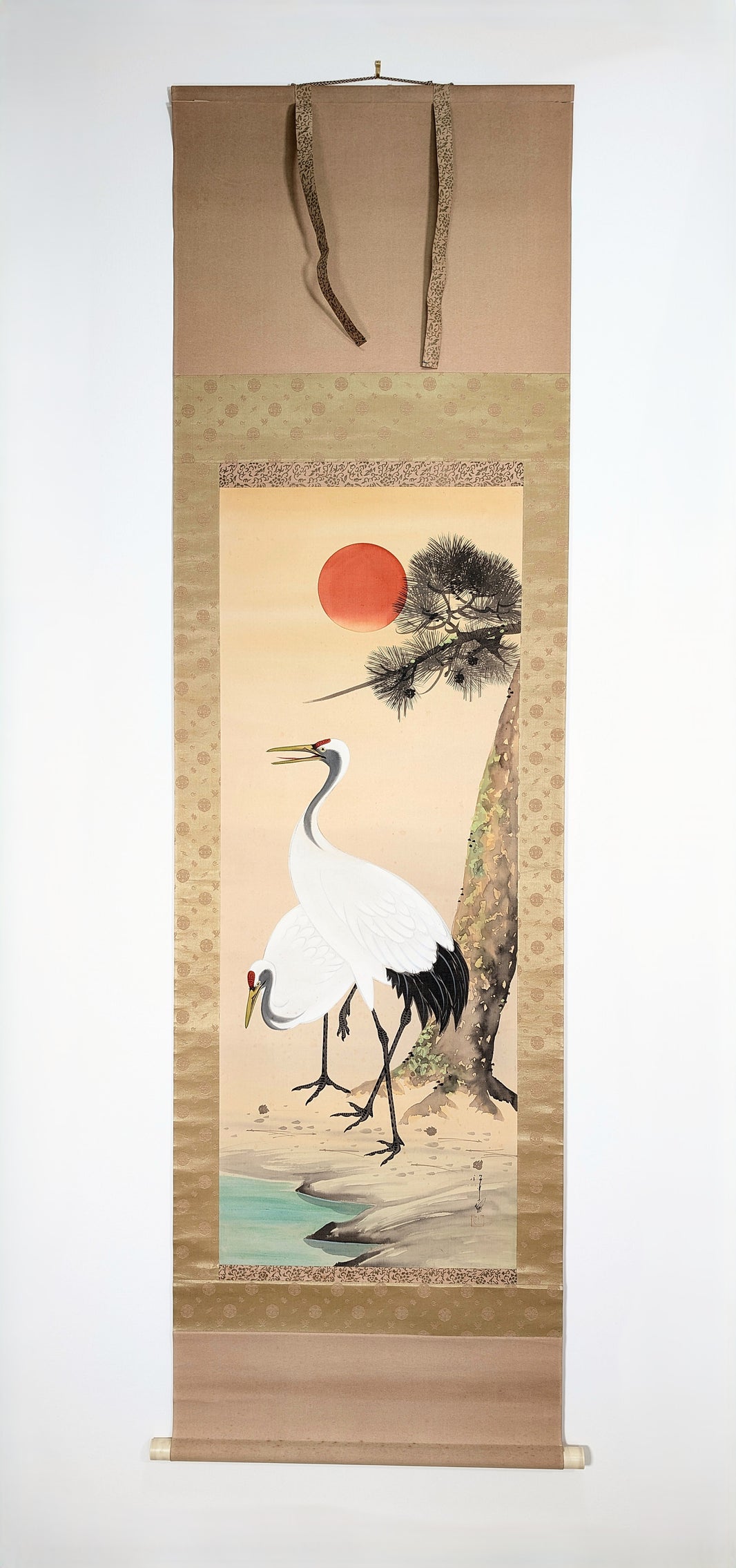 Kakejiku japonais du XXe siècle, probablement époque Shōwa, représentant deux grues sous un pin et un soleil rouge, peinture signée à la main sur soie avec montage en brocart de soie.
