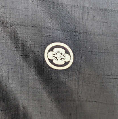 Gros plan sur le kamon japonais Maru Mokkō, emblème familial appliqué sur un haori en soie noire