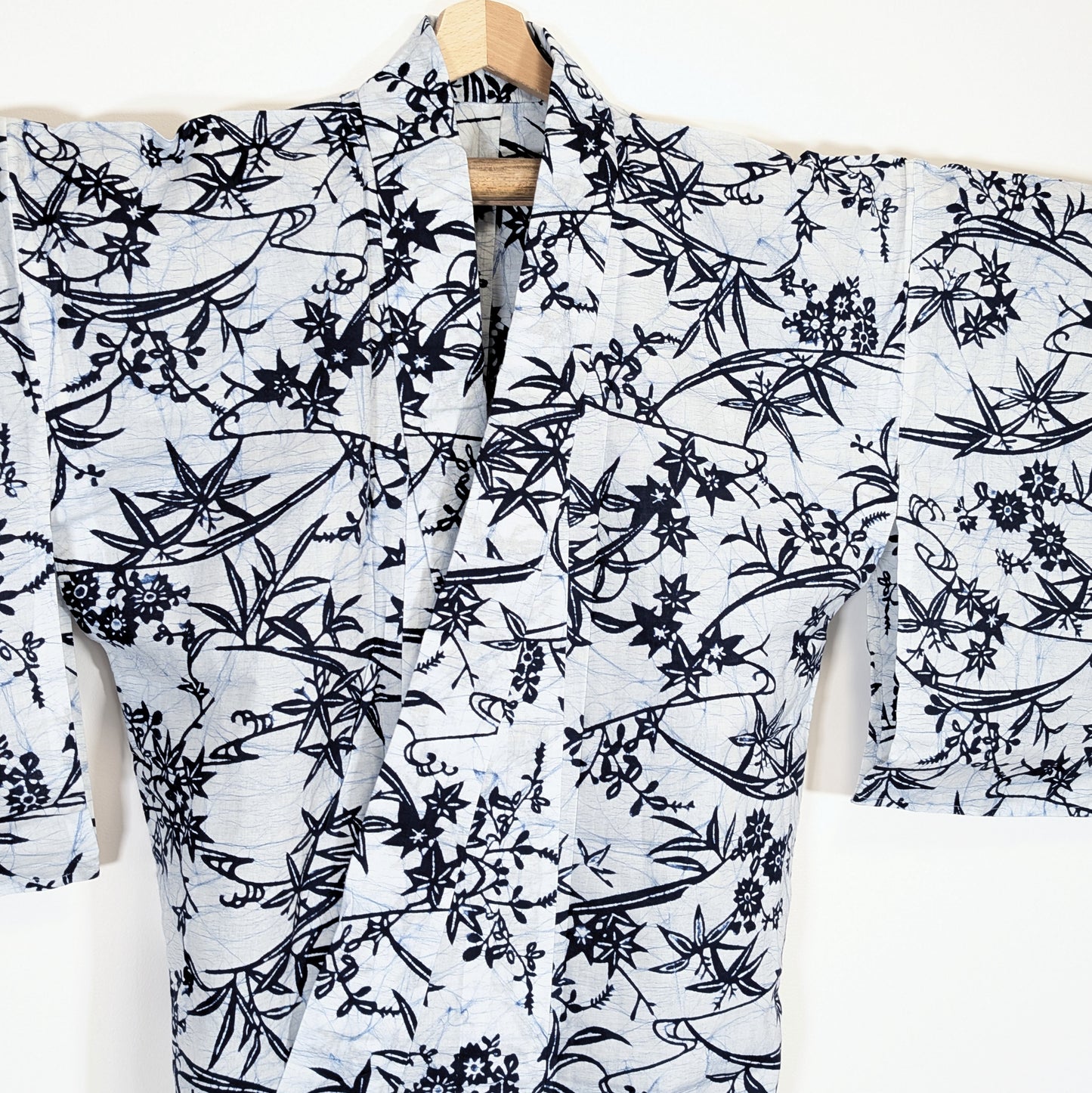 Vue de face d’un yukata japonais blanc à motifs végétaux bleus, érables momiji et bambou stylisé