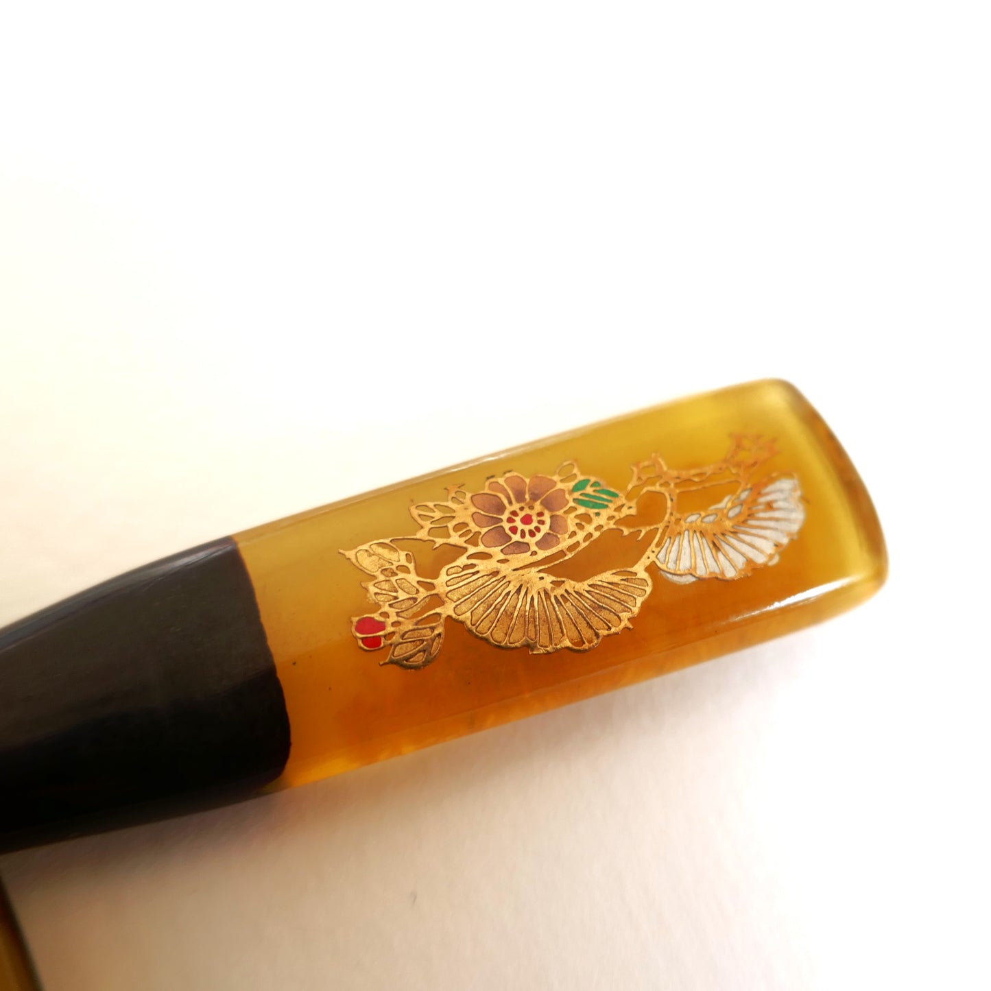 Détail du kogai japonais en imitation bekko, décor floral finement laqué maki-e doré, accessoire de coiffure traditionnel.
