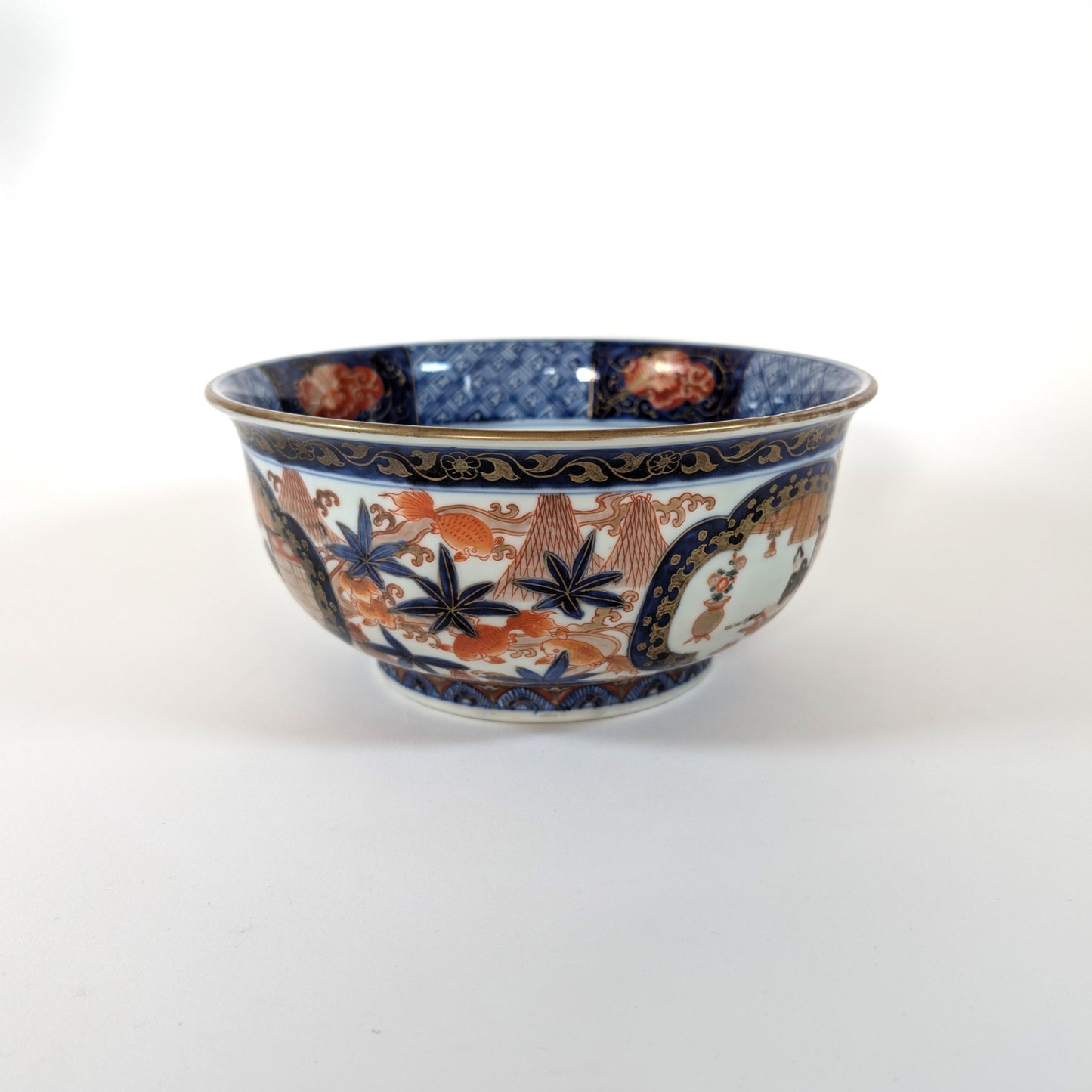 Bol ancien japonais de style Imari, décor rouge, bleu et or avec paysages et poissons rouges.