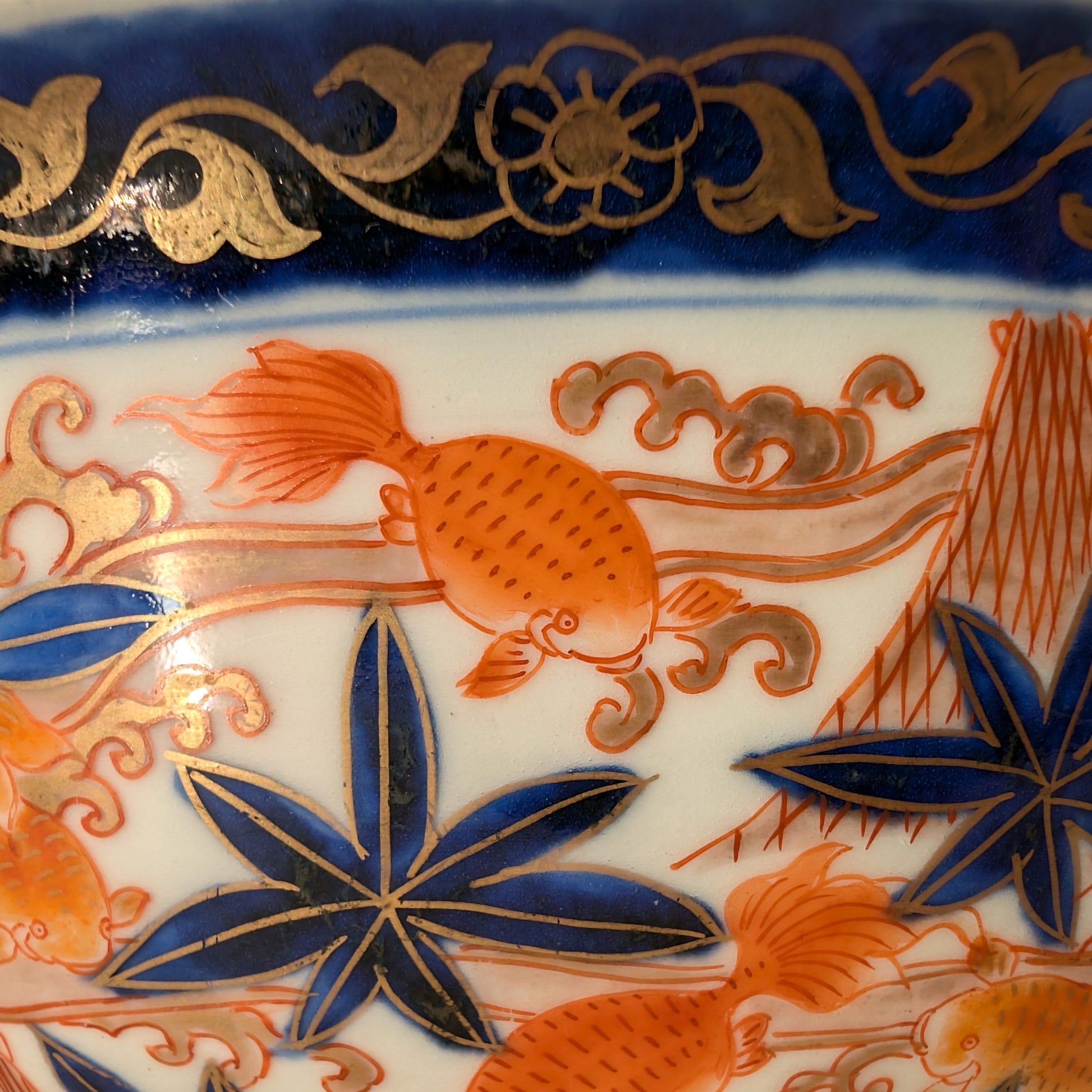 Gros plan sur un poisson rouge peint à la main sur porcelaine japonaise Imari, décor traditionnel bleu et or.