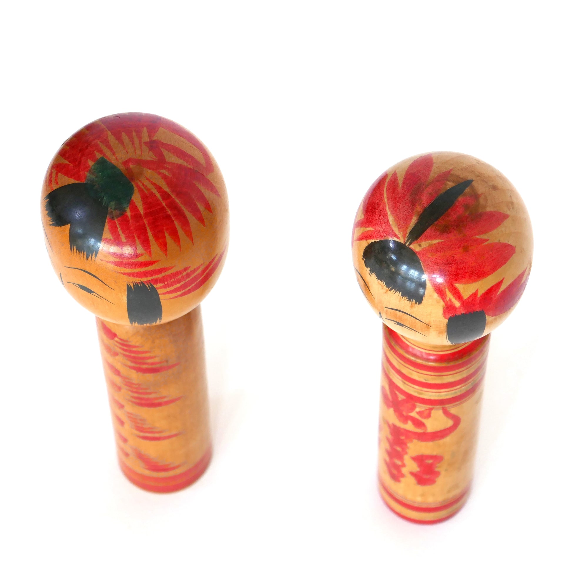 Kokeshi artisanales japonaises vues en plongée, présentant la coiffure et les fleurs peintes.