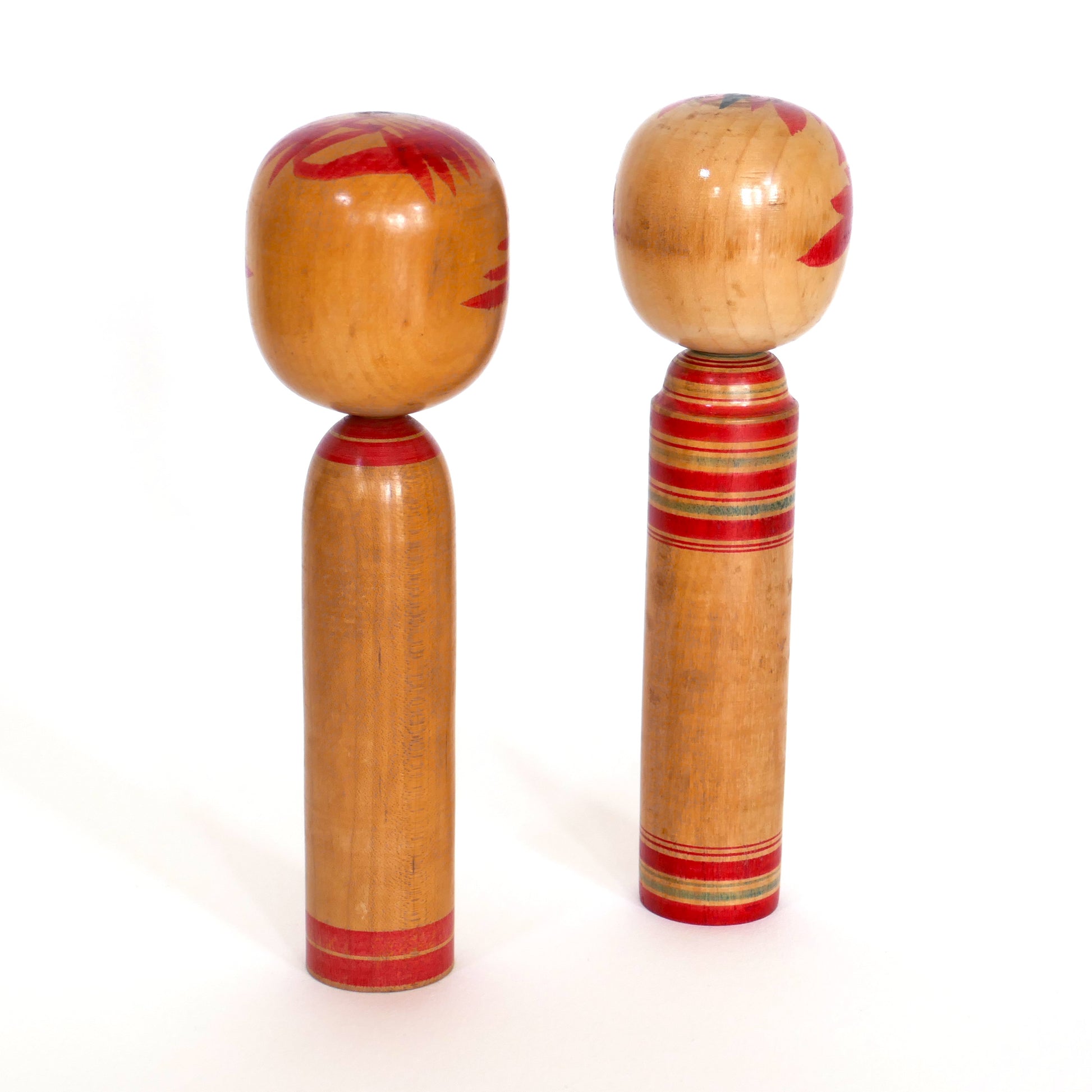 Vue arrière de deux kokeshi japonaises montrant les finitions du bois naturel.