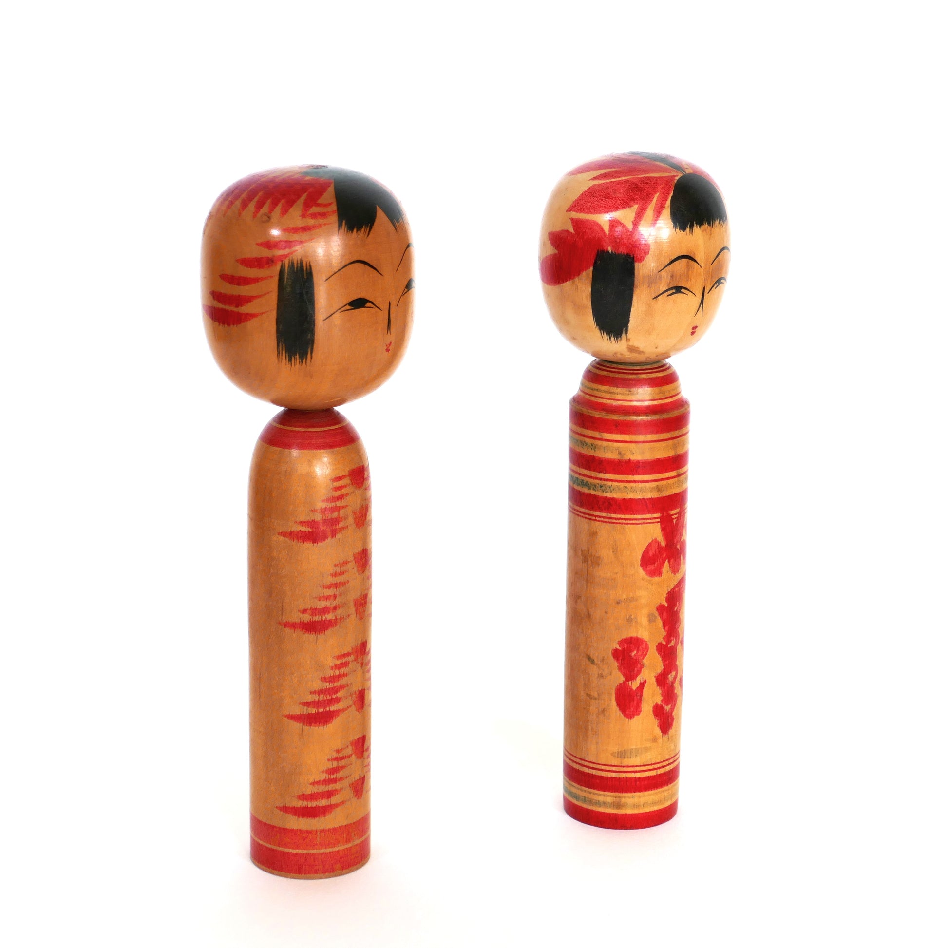 Kokeshi artisanales japonaises photographiées de profil, montrant leurs décors latéraux.