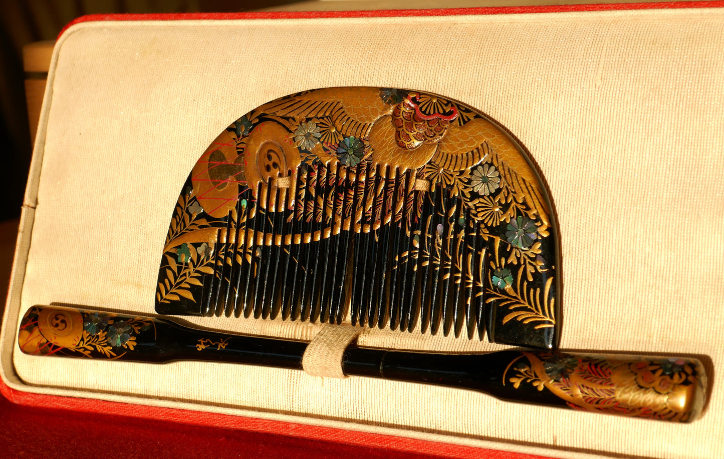Vue de face de l’ensemble Kushi et Kogai Edo dans sa boîte d’origine, avec décor floral et phénix en dorure et nacre.