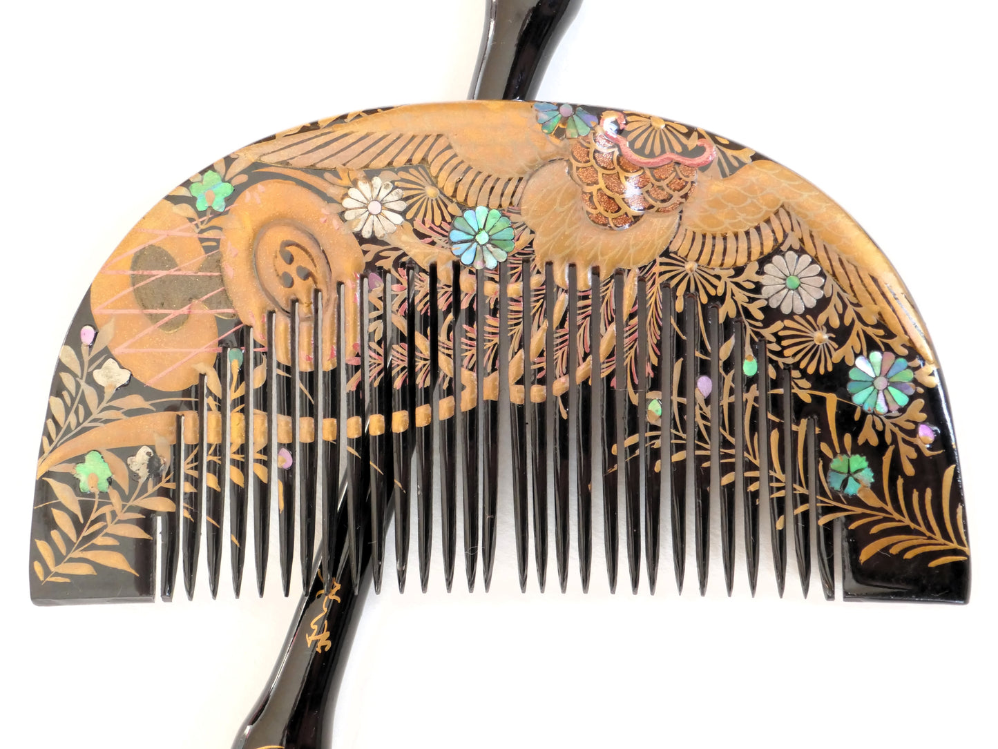 Vue rapprochée du peigne japonais ancien Kushi avec décor de phénix, fleurs en nacre et feuillage doré.