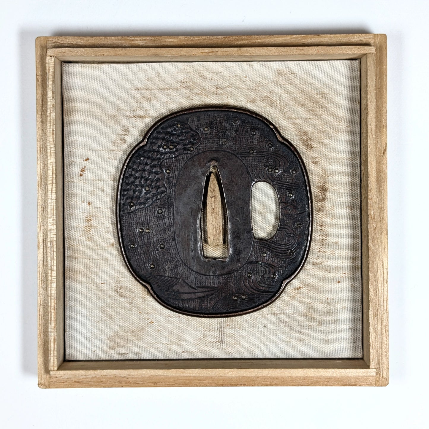 Tsuba Edo tardif en fer forgé, style Shoami, présentée dans un cadre décoratif, motif maritime gravé.