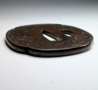 Tsuba japonaise Edo tardif en fer forgé, vue en angle rasant, style Shoami, décor gravé de vagues et bateau, fitting de wakizashi.