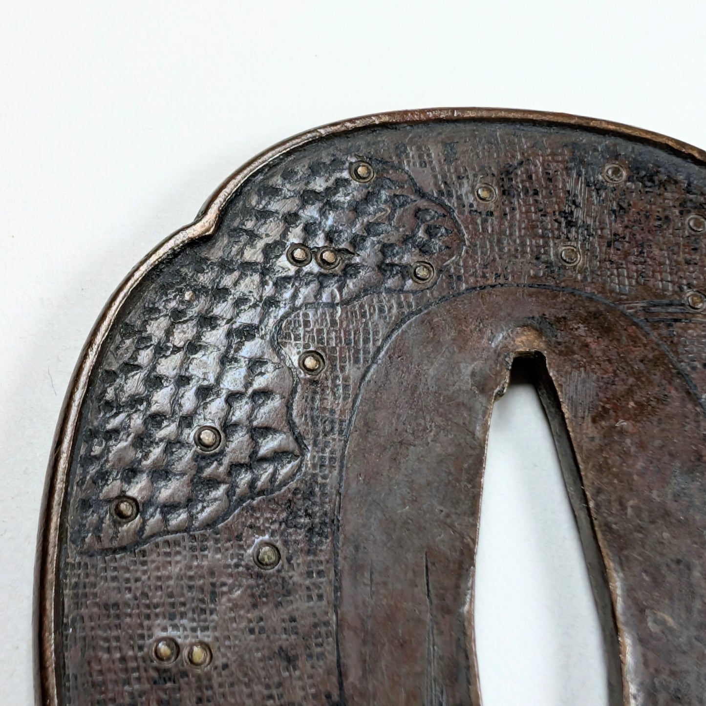 Détail de texture d'une tsuba Shoami Edo, décor de vagues et incrustations en laiton, fer ancien.