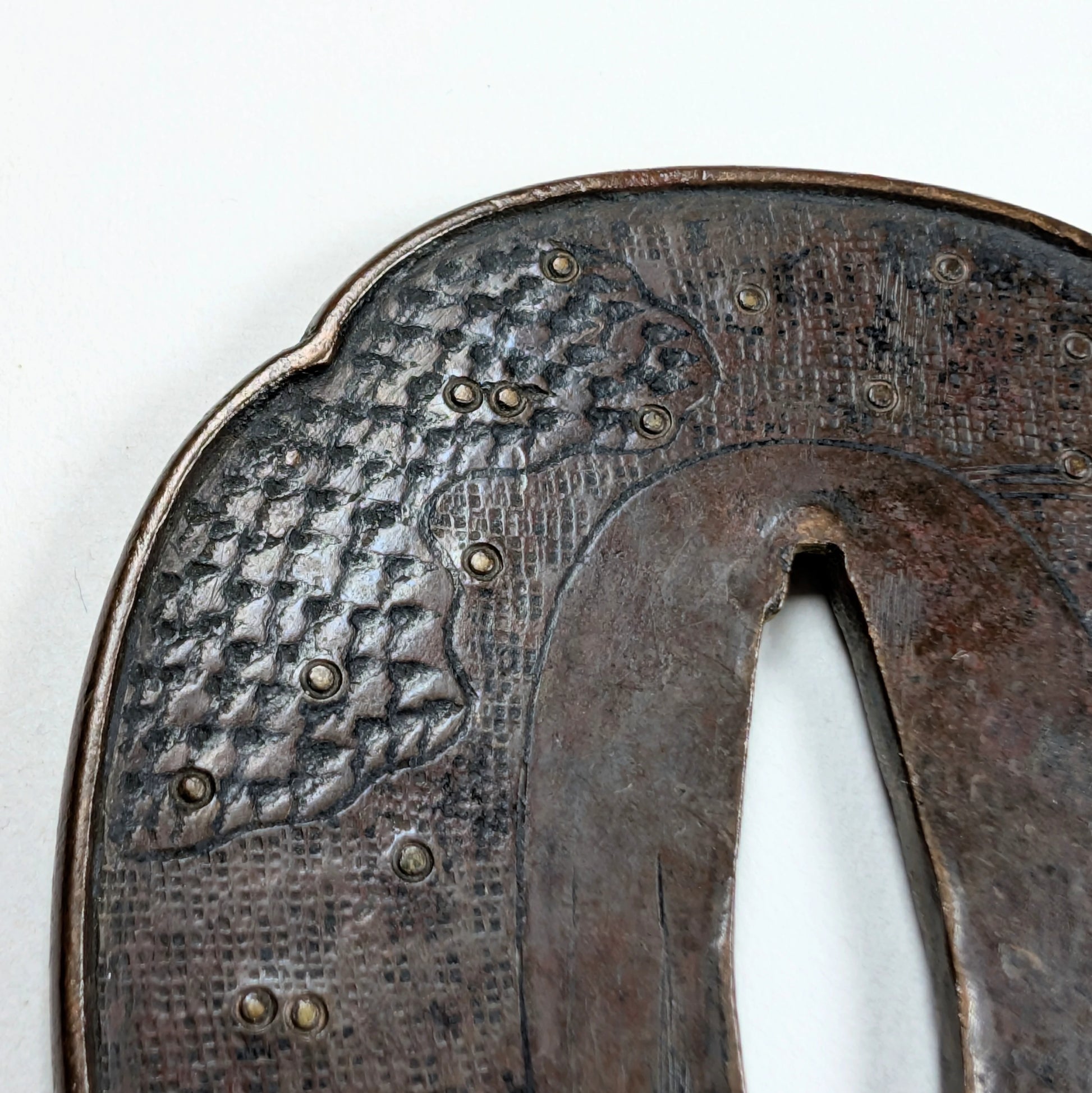 Détail de texture d'une tsuba Shoami Edo, décor de vagues et incrustations en laiton, fer ancien.