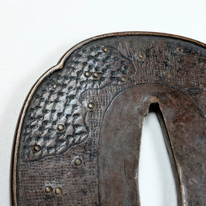 Détail de texture d'une tsuba Shoami Edo, décor de vagues et incrustations en laiton, fer ancien.