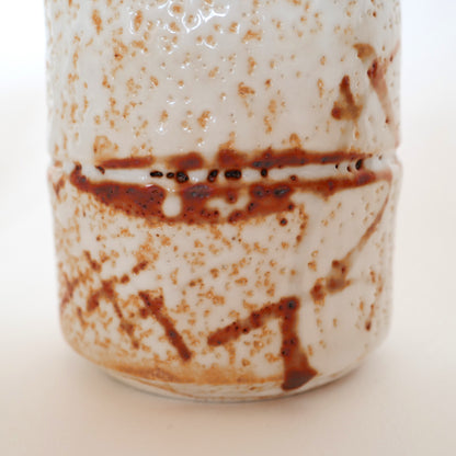 Détail rapproché d’une tasse Shino-yaki, glaçure blanche épaisse et trace ferreuse naturelle.