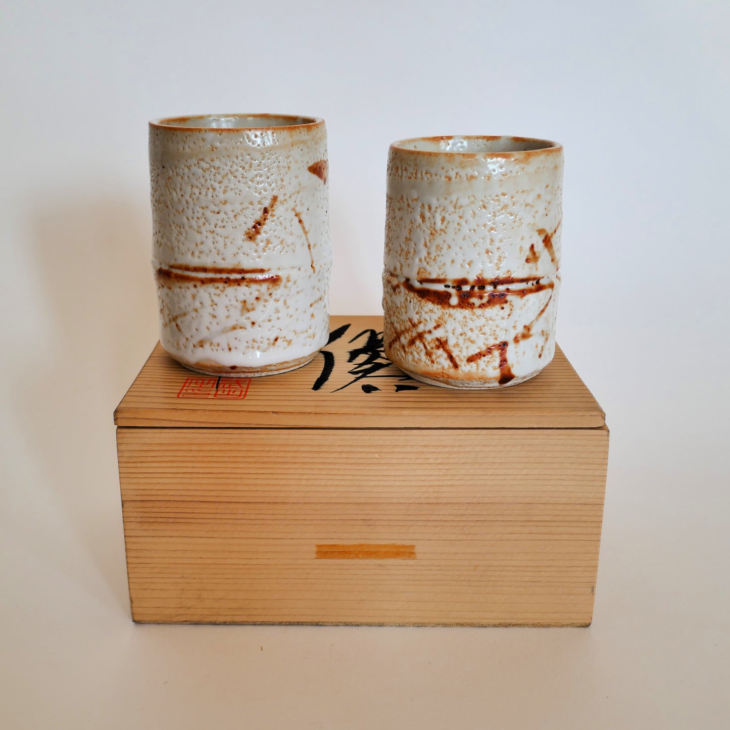 Deux tasses japonaises Shino-yaki posées sur leur boîte en bois calligraphiée, vue esthétique de présentation.