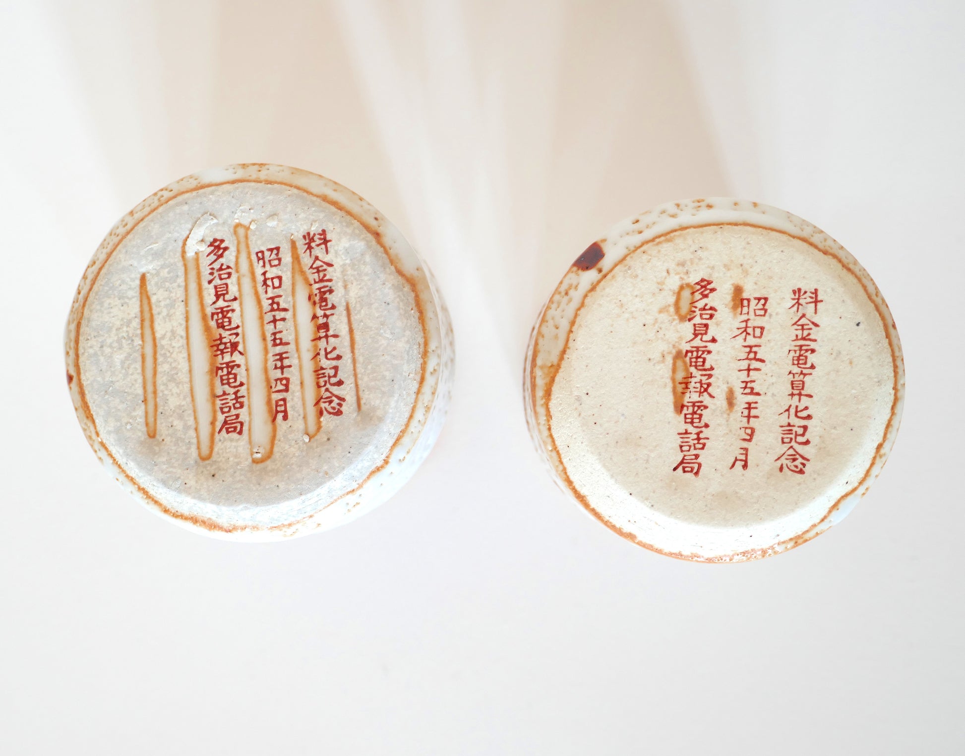 Vue du dessous de deux tasses japonaises Shino-yaki avec inscriptions commémoratives en rouge, datées de l’ère Shōwa.