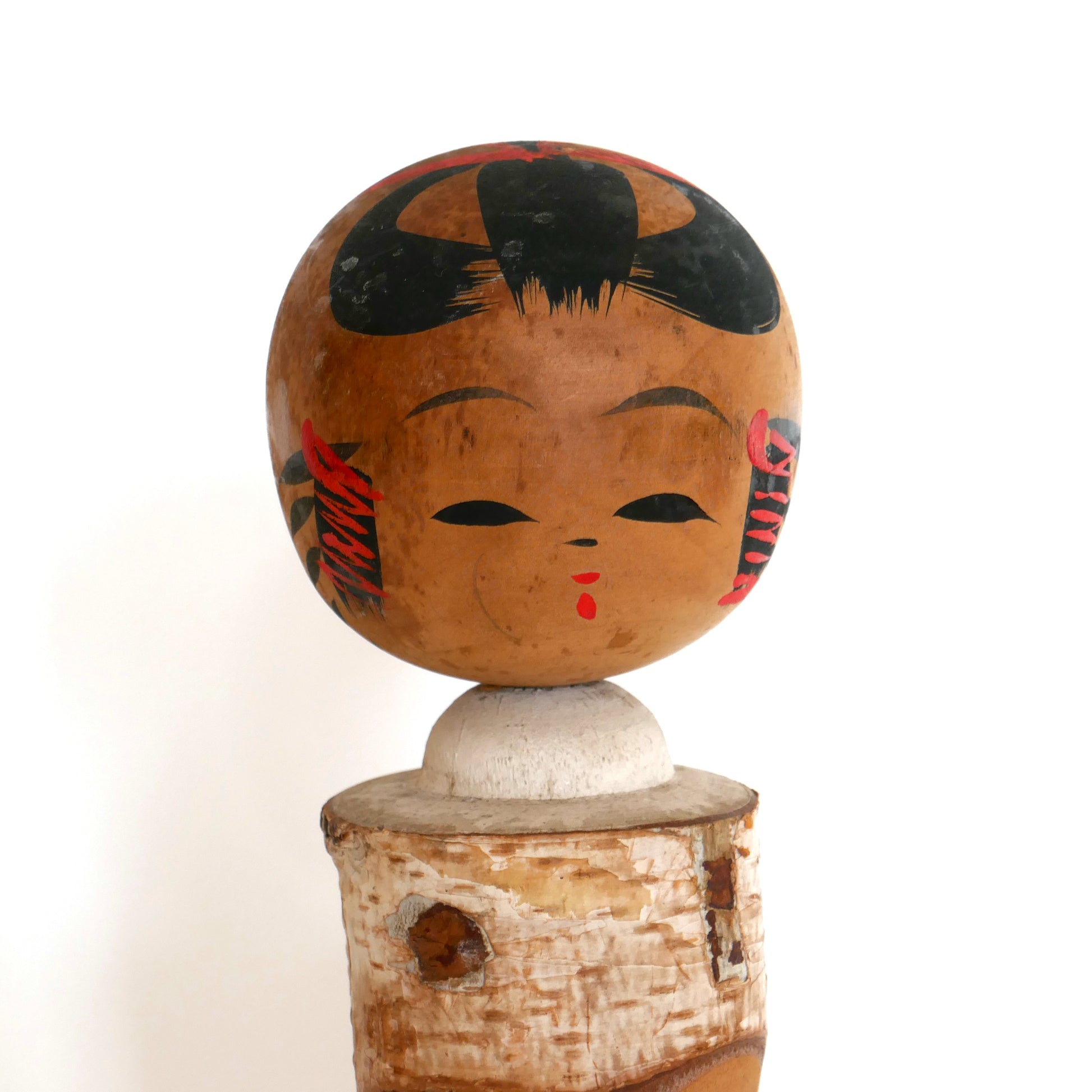 Visage peint à la main d’une kokeshi poupée japonaise souvenir vintage fabriquée à Akakura au Japon.