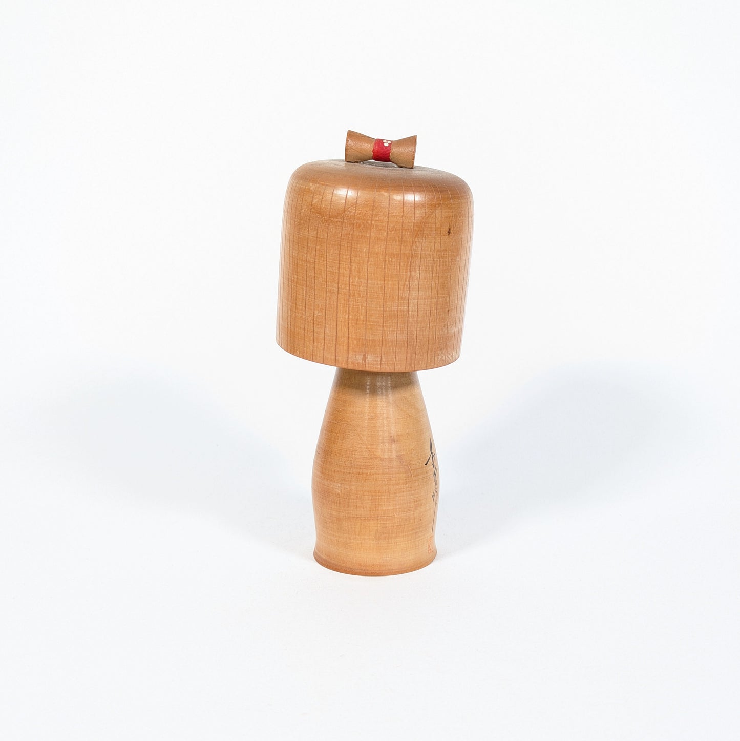 Kokeshi ancienne japonaise de l’époque Shōwa, vue arrière montrant la patine du bois blond et le chignon rouge décoratif