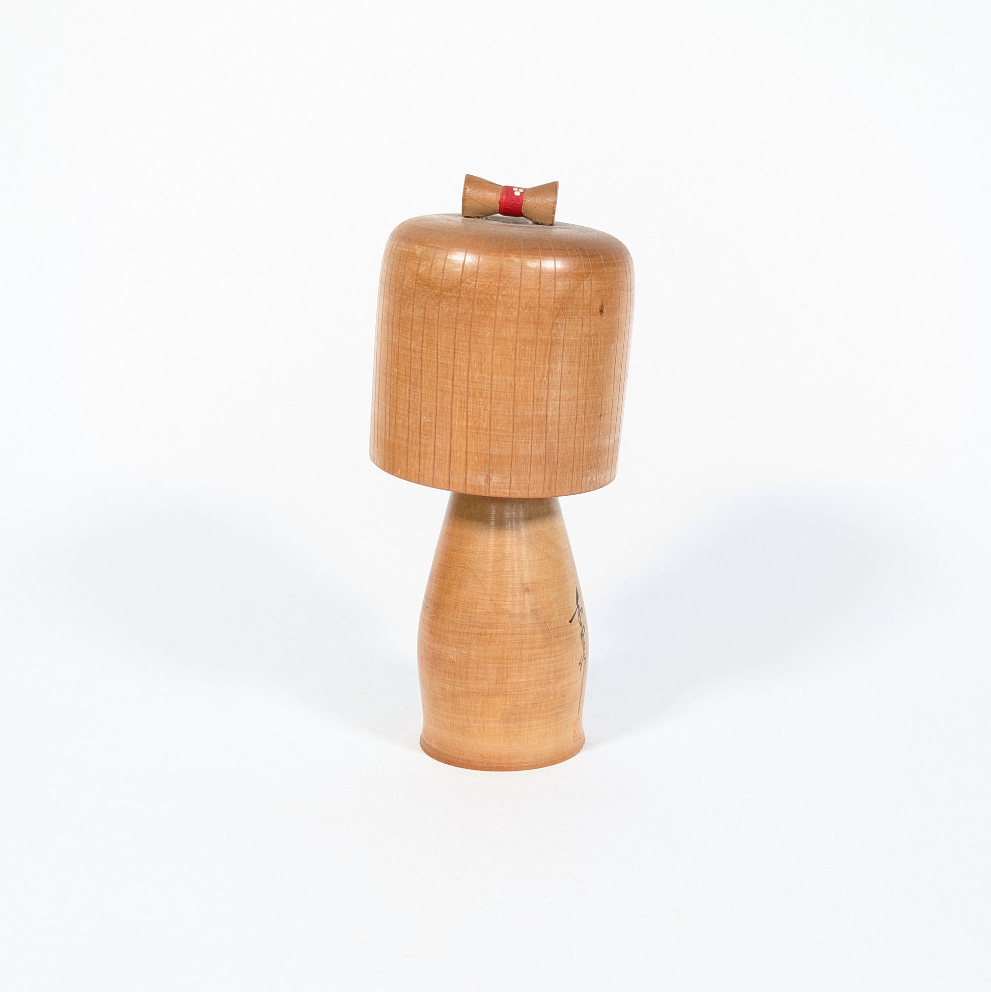 Kokeshi ancienne japonaise de l’époque Shōwa, vue arrière montrant la patine du bois blond et le chignon rouge décoratif