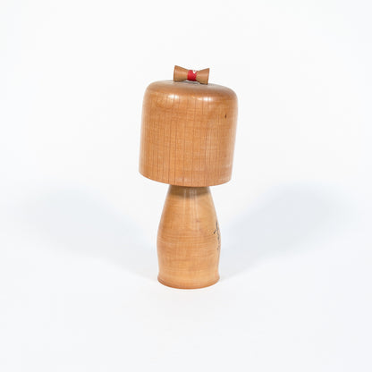 Kokeshi ancienne japonaise de l’époque Shōwa, vue arrière montrant la patine du bois blond et le chignon rouge décoratif