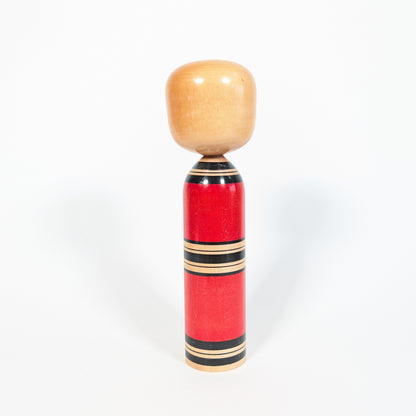 Dos d’une kokeshi ancienne sosaku de l’ère Showa, corps rouge à lignes noires et bois naturel
