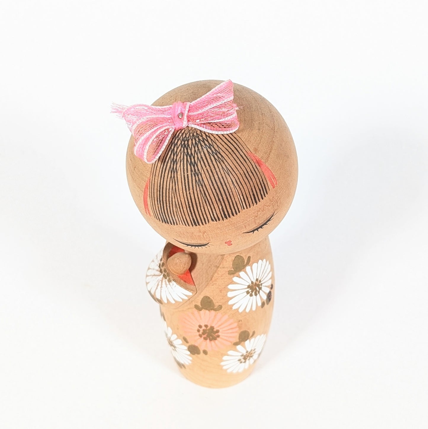 vue dessus kokeshi sosaku d'aoki ryoka coiffure traditionnelle japonaise avec ruban rose bois tourné
