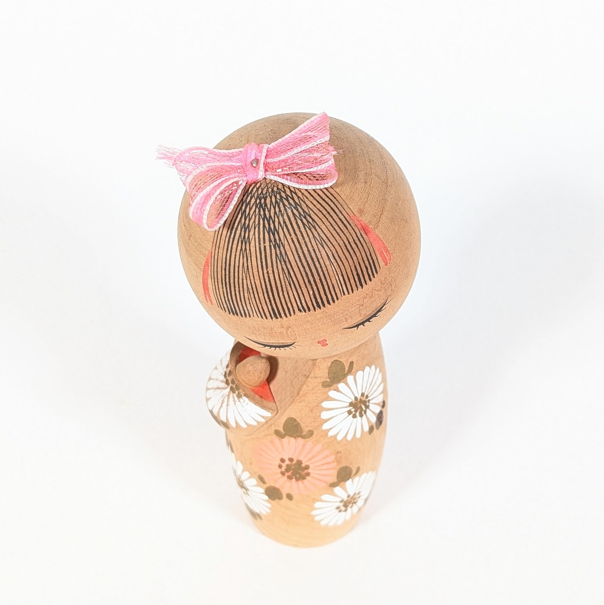 vue dessus kokeshi sosaku d'aoki ryoka coiffure traditionnelle japonaise avec ruban rose bois tourné