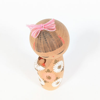 vue dessus kokeshi sosaku d'aoki ryoka coiffure traditionnelle japonaise avec ruban rose bois tourné