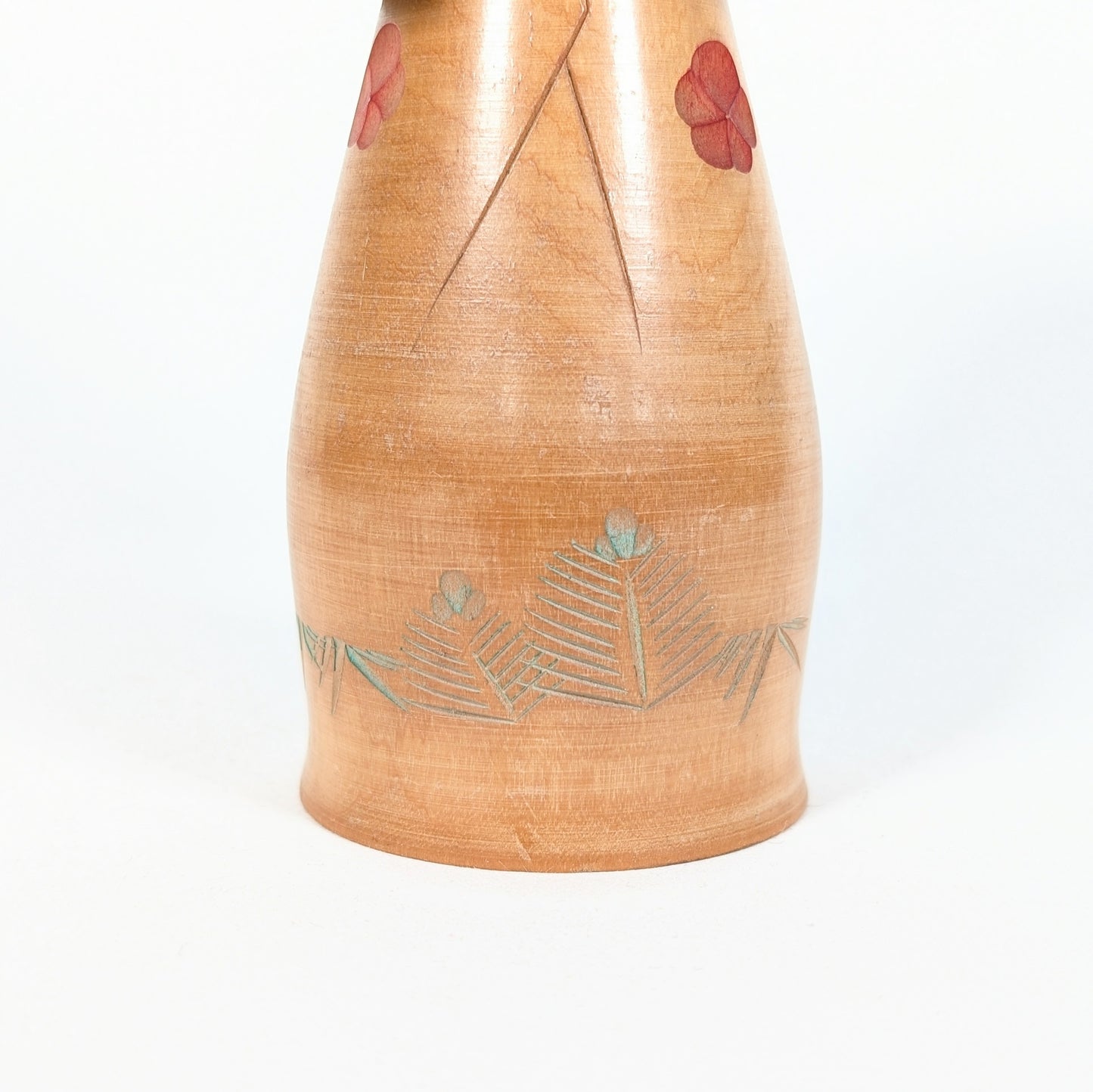 Kokeshi artisanale en bois Hōshun, détail du kimono avec fleurs de ume rouges et feuilles gravées teintées vert pâle