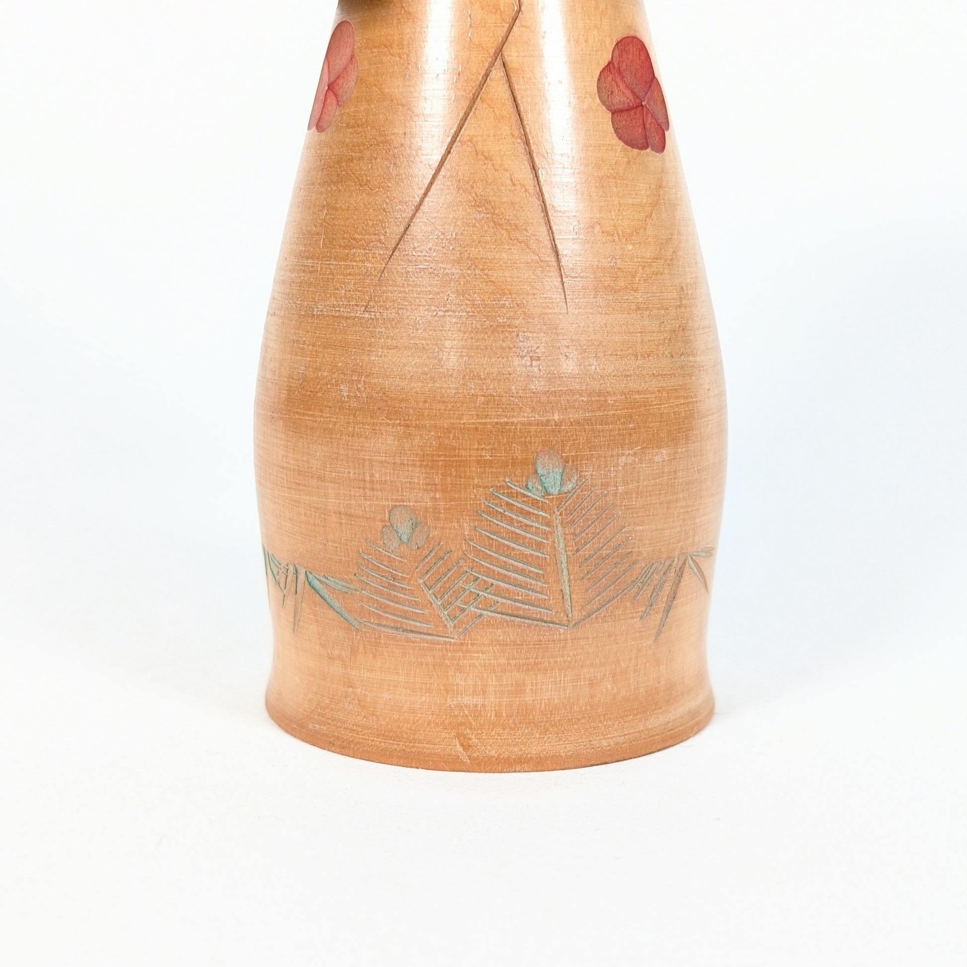 Kokeshi artisanale en bois Hōshun, détail du kimono avec fleurs de ume rouges et feuilles gravées teintées vert pâle