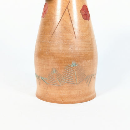 Kokeshi artisanale en bois Hōshun, détail du kimono avec fleurs de ume rouges et feuilles gravées teintées vert pâle
