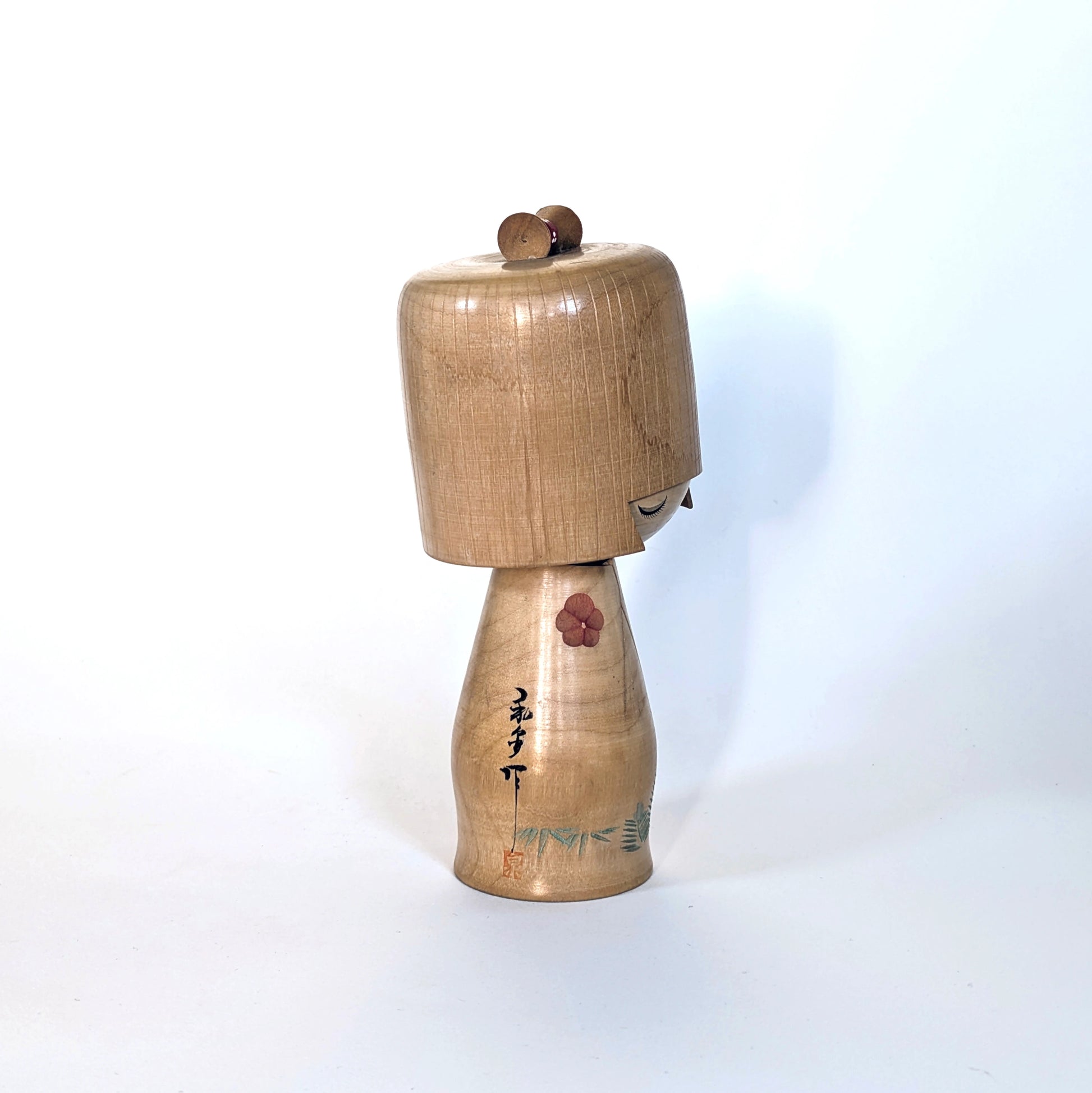 Vue de profil droit d’une kokeshi sōsaku Ueda Izumi, création artistique en bois.