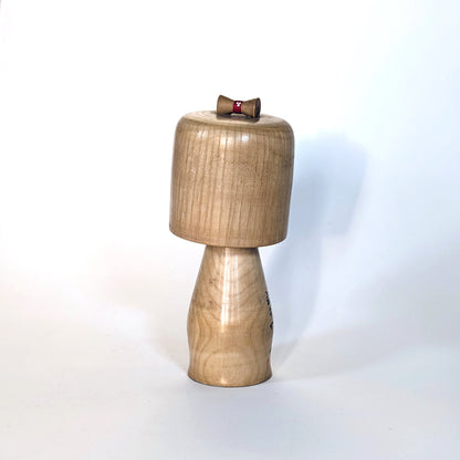 Vue arrière d’une kokeshi japonaise en bois par Ueda Izumi, finition naturelle.