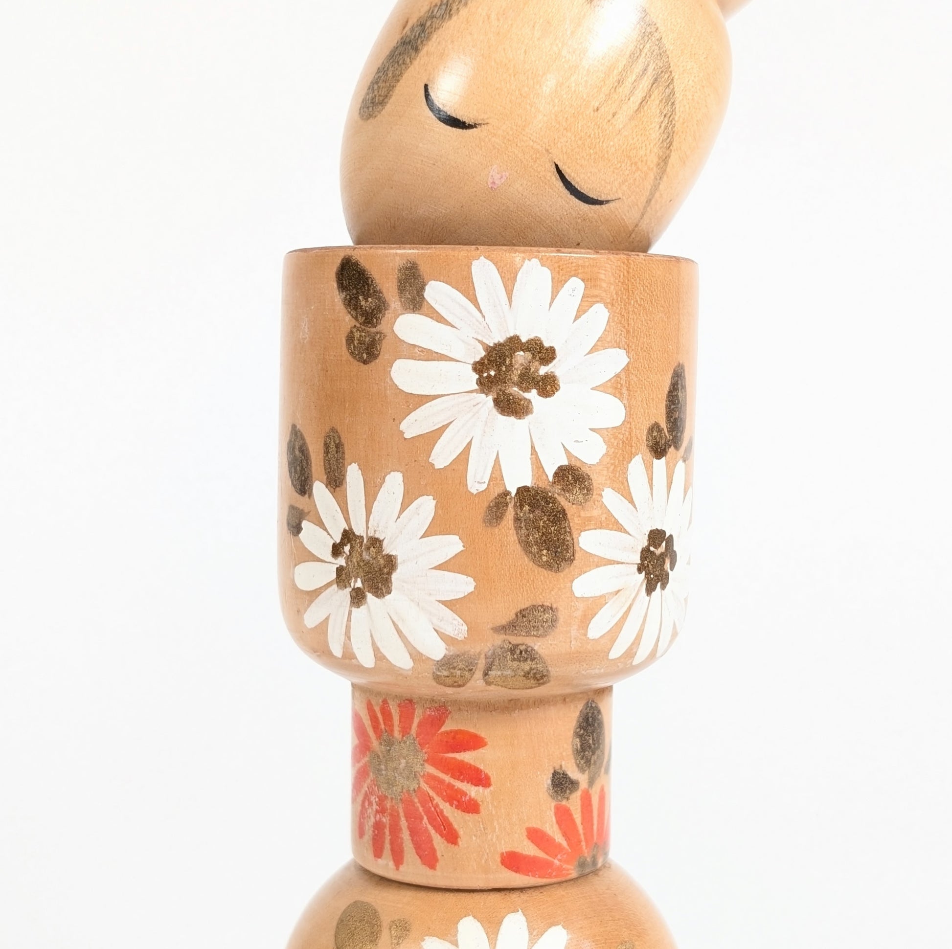Détail des chrysanthèmes blancs peints sur une kokeshi d’Ishida Tomio, avec feuillage et centres dorés.