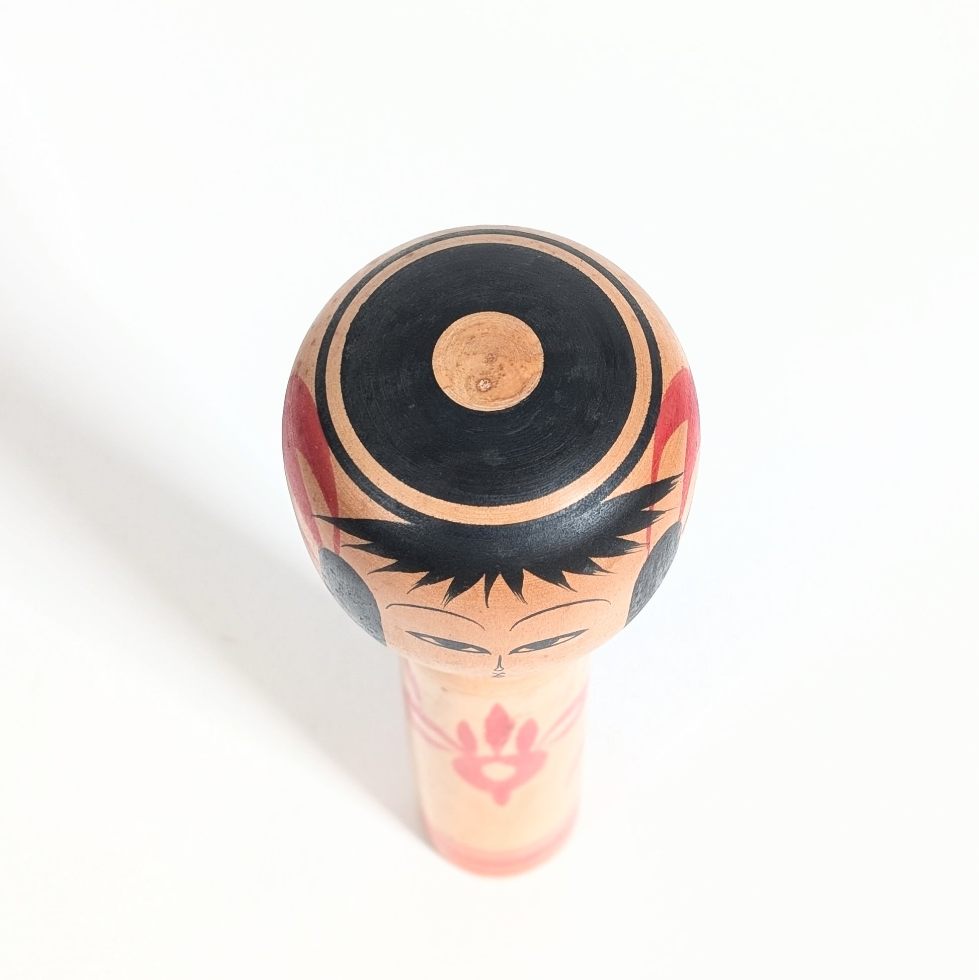 Vue du dessus d’une kokeshi de collection par Yasuaki Katō avec visage traditionnel et bois tourné.