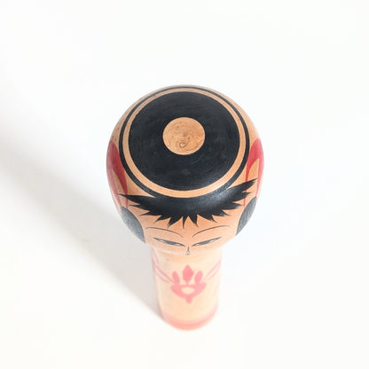 Vue du dessus d’une kokeshi de collection par Yasuaki Katō avec visage traditionnel et bois tourné.