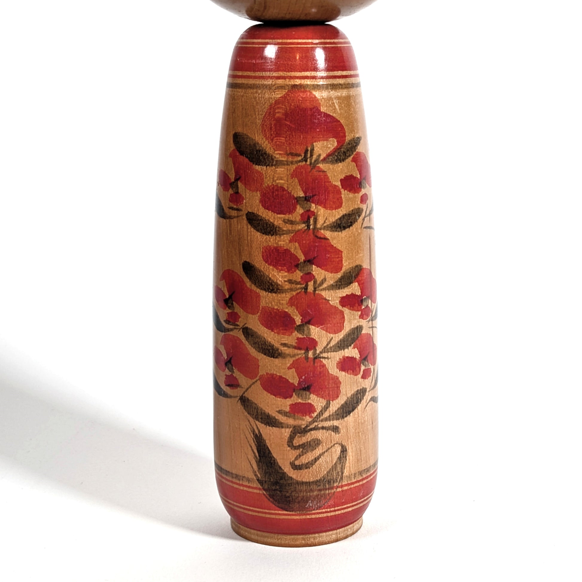 Motif floral peint à la main sur le corps d’une kokeshi japonaise en bois, poupée traditionnelle japonaise de l’école Yamagata
