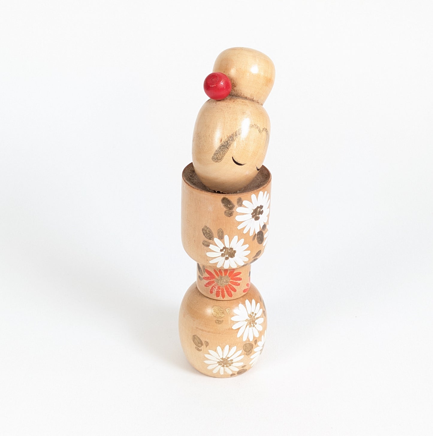 Kokeshi créative japonaise d’Ishida Tomio en bois naturel, tête inclinée et décor floral peint à la main.