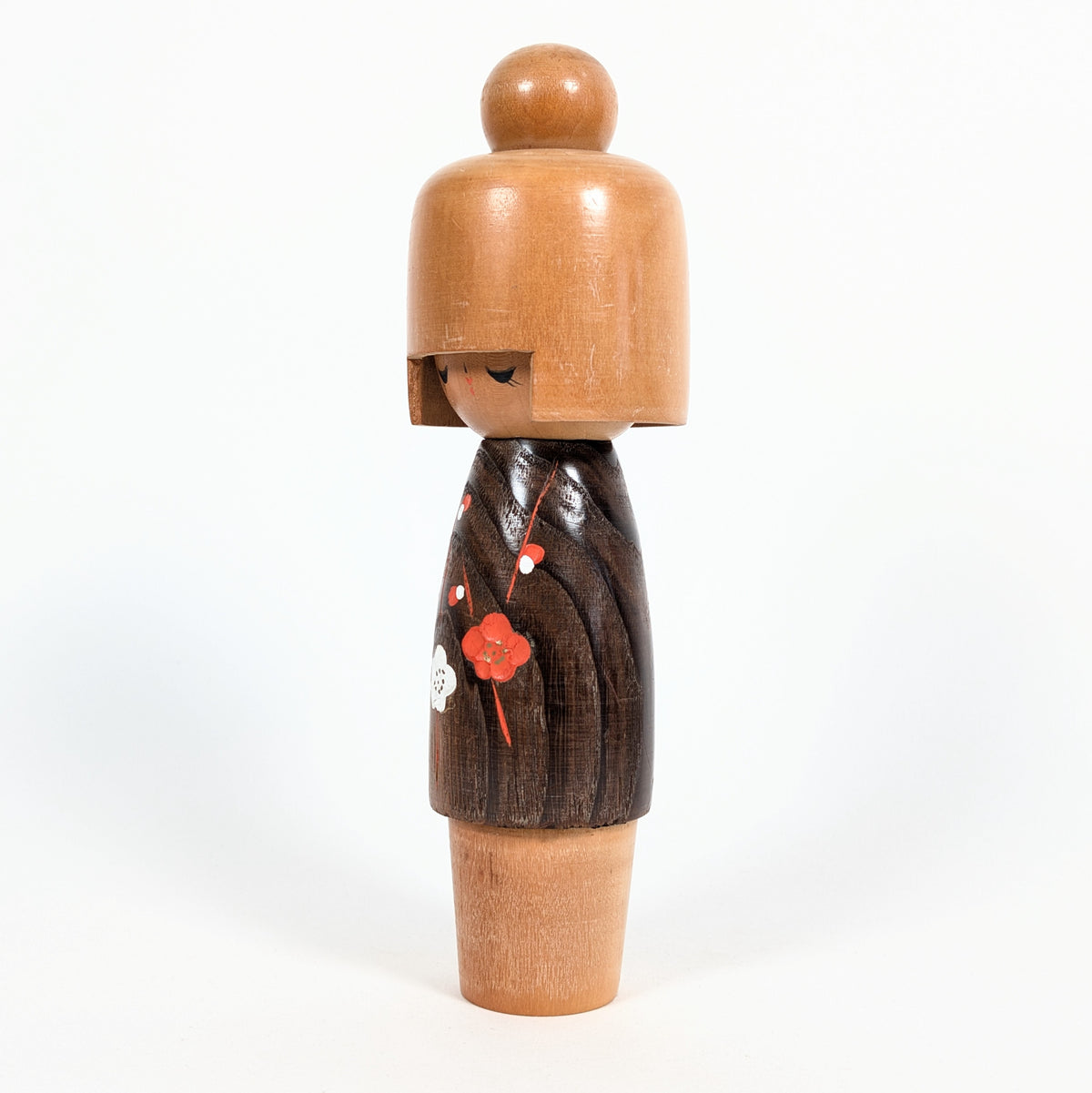 Kokeshi créative japonaise de type sōsaku, modèle Koigokoro d'Usaburo, vue de profil avec un kimono brun foncé orné de fleurs rouges et blanches.