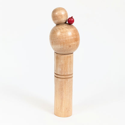 Vue arrière d'une kokeshi créative japonaise vintage en bois naturel avec chignon sculpté et ornement rouge