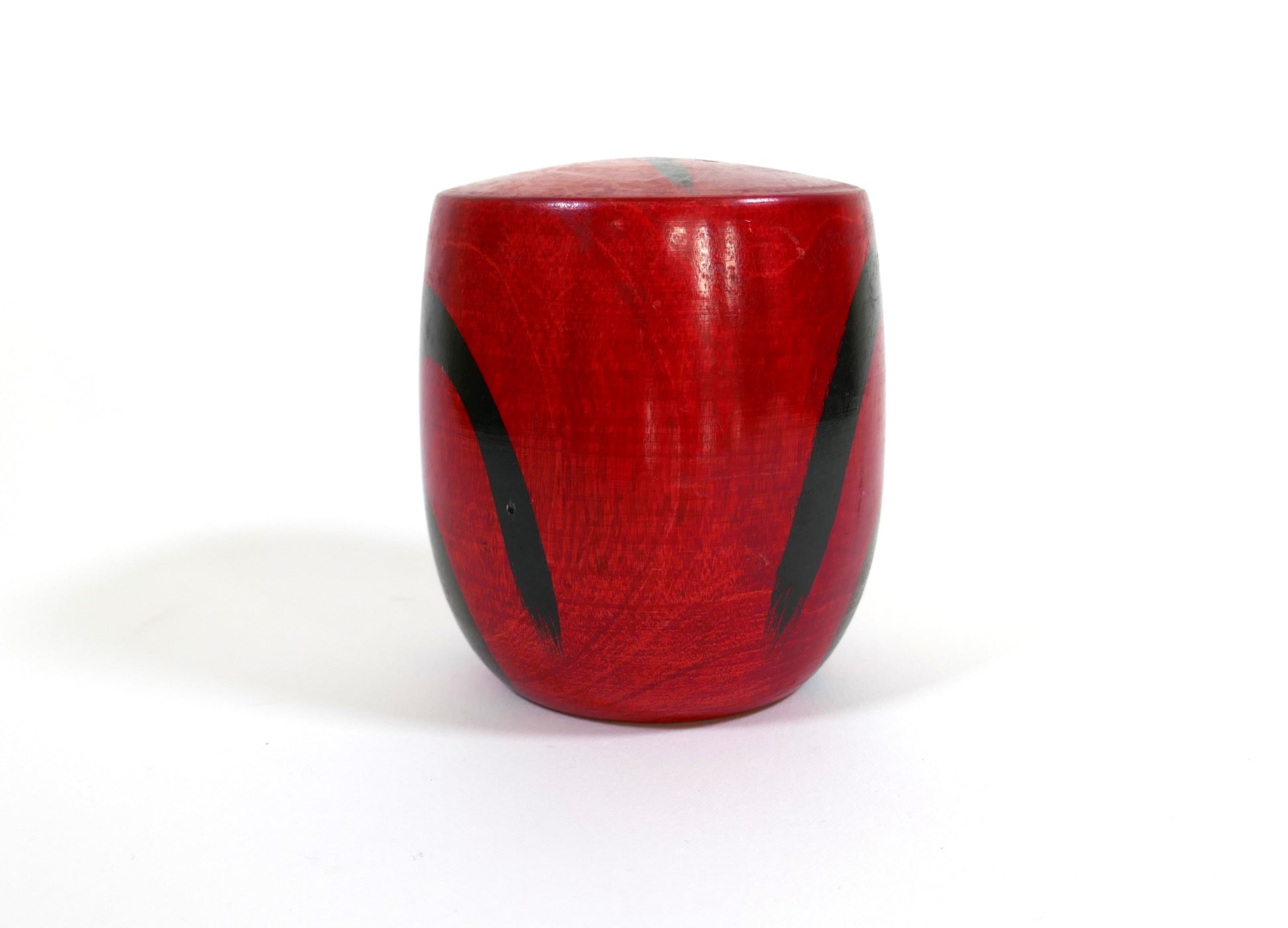 Vue arrière d’une kokeshi Daruma peinte en rouge avec décor noir traditionnel
