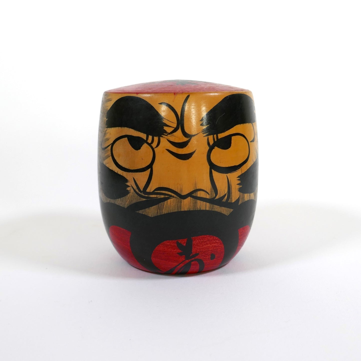 Kokeshi Daruma traditionnelle vue de face, au visage expressif en rouge et noir