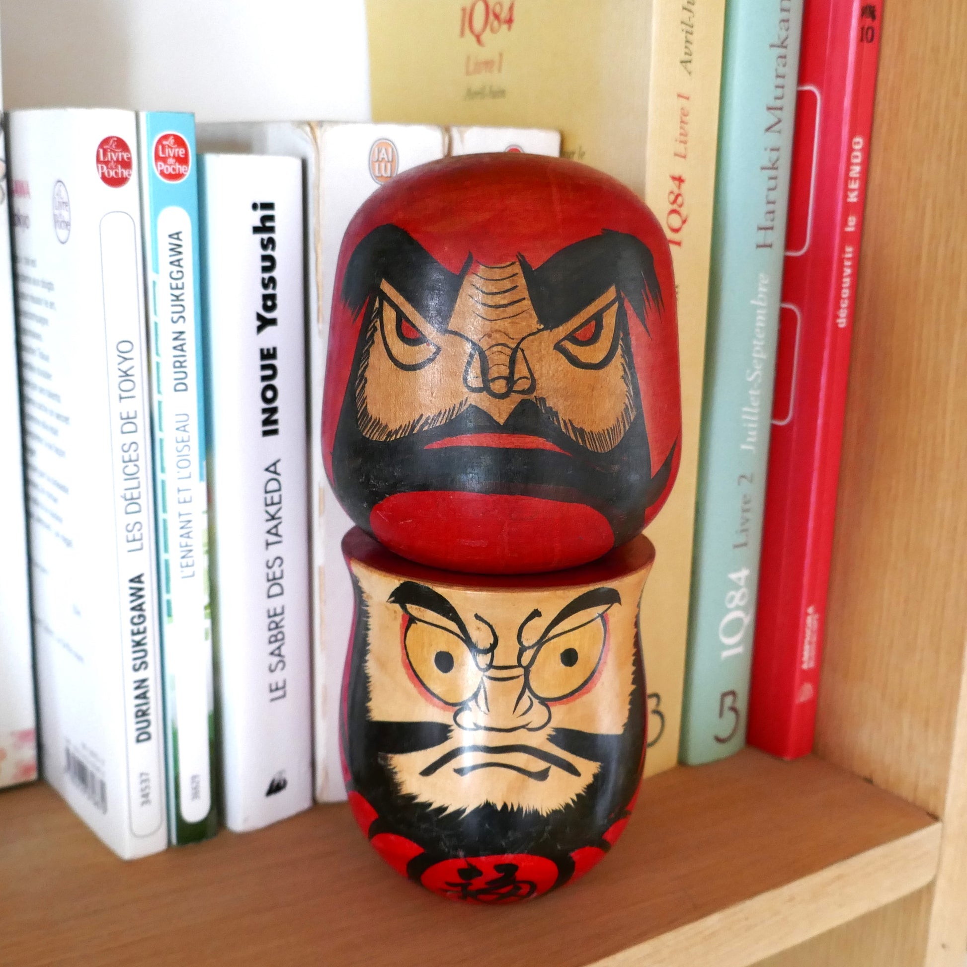 Deux kokeshi Daruma vintage en décoration sur une étagère, dont une par l’artisan Kawamura, style japonais Shōwa